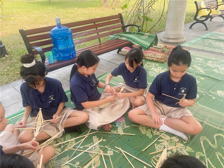 A group of girls sitting on a green mat

Description automatically generated
