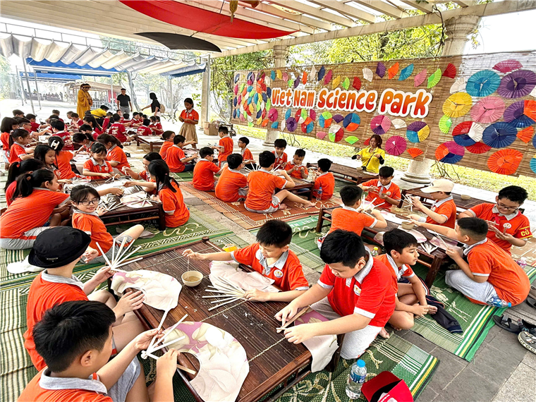 A group of children sitting on the ground in front of a sign

Description automatically generated