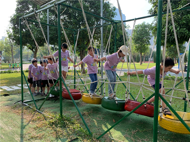 A group of kids playing on a swing

Description automatically generated
