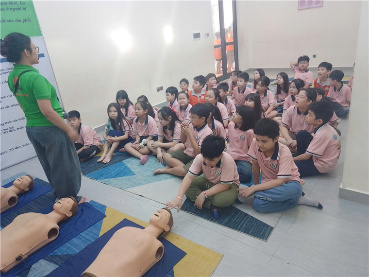 A group of children sitting on the floor with a person in the background

Description automatically generated