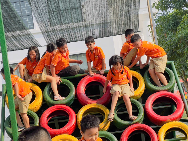 A group of children climbing on a wall of tires

Description automatically generated