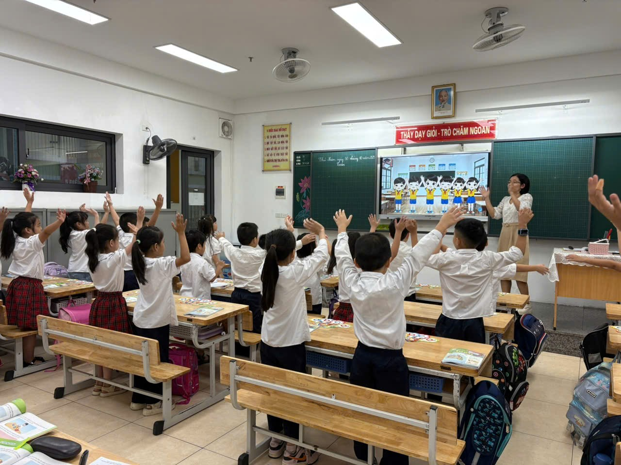 A group of students raising their hands in a classroom

AI-generated content may be incorrect.