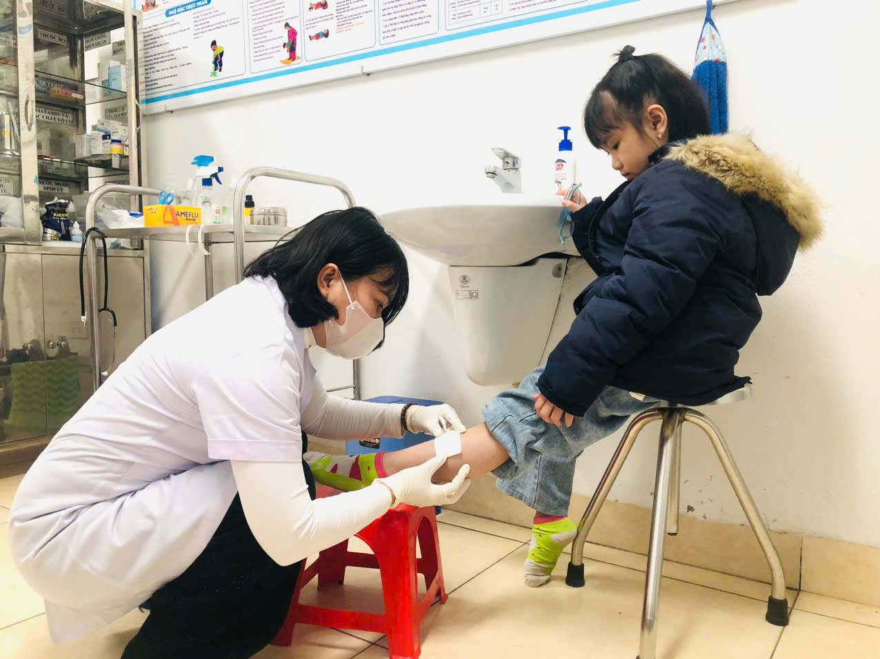 A person in a white coat and mask getting a blood shot of a child

AI-generated content may be incorrect.