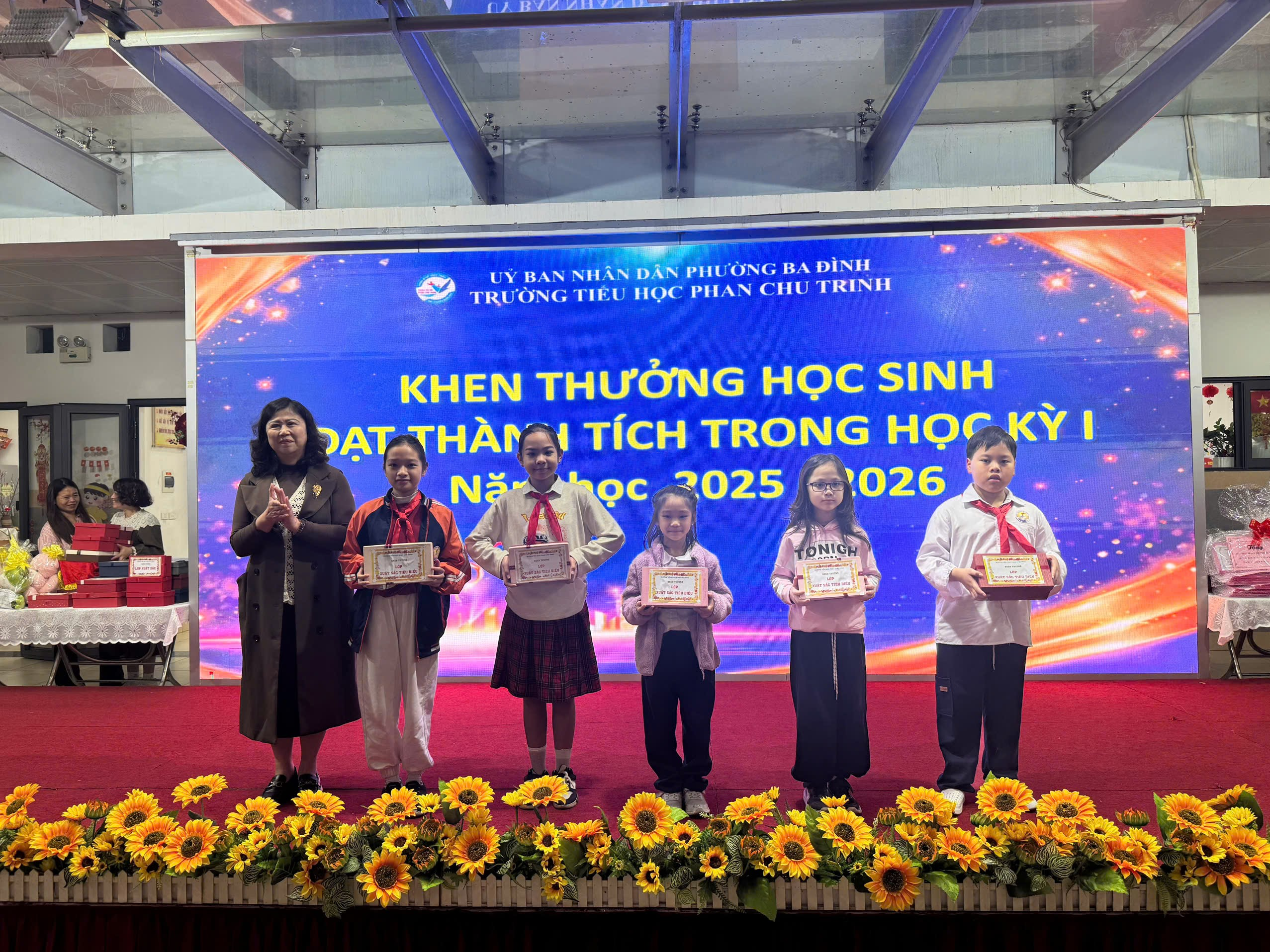 A group of people standing on a stage with flowers and a large screen

AI-generated content may be incorrect.